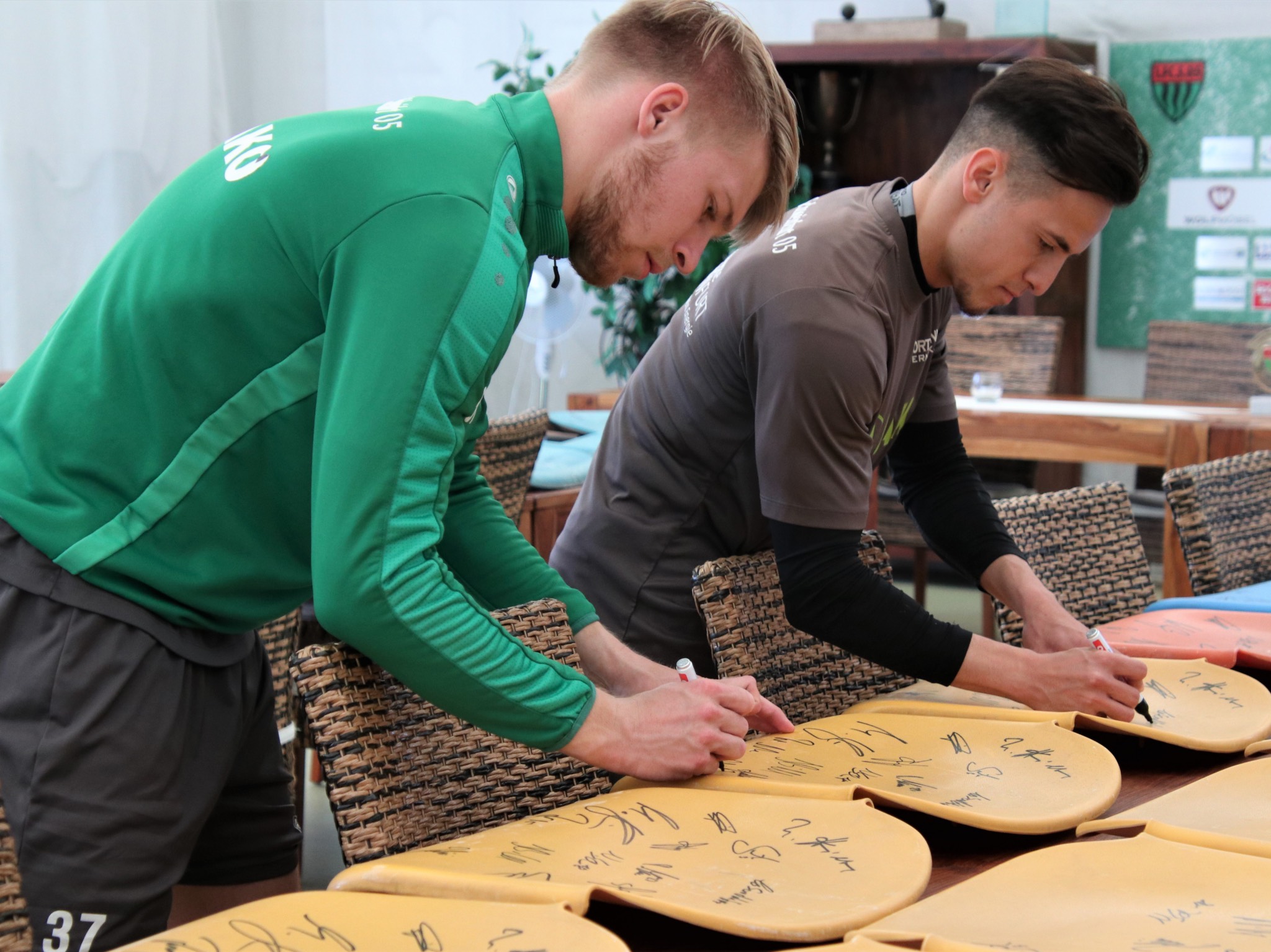 Stefan Maderer und Gianluca Lo Scrudato unterschreiben die alten Sitzschalen. Foto: 1.FC Schweinfurt 1905