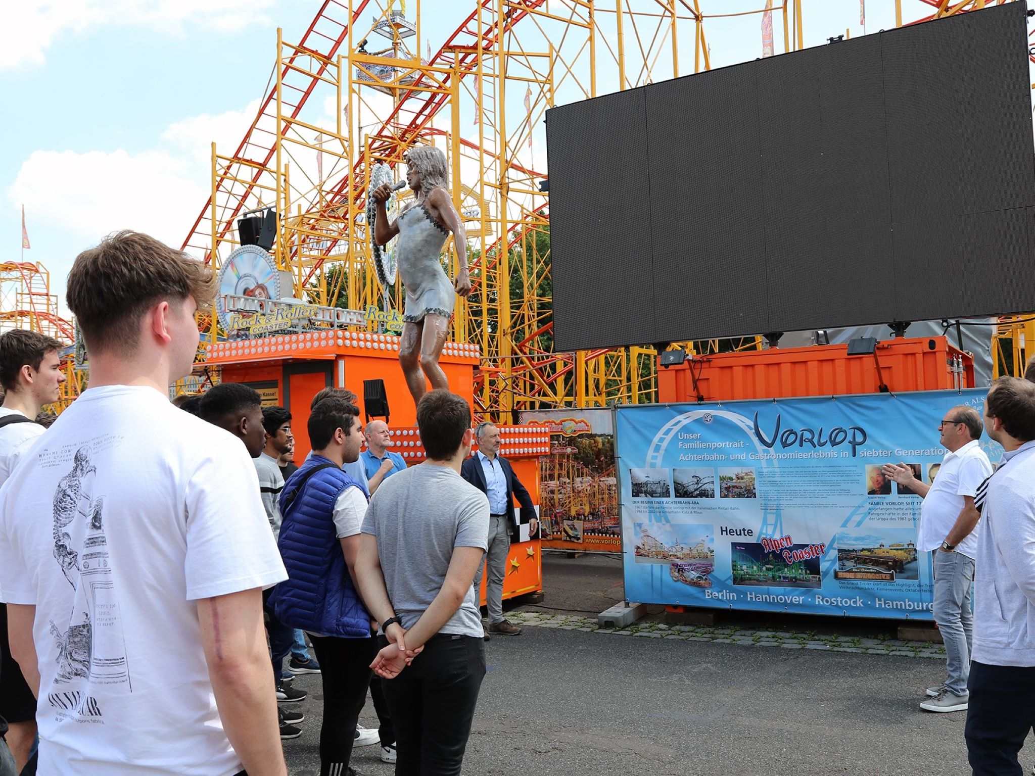 Achterbahn-Betreiber Lutz Vorlop (3. v. r. ) erzählt die Hintergrundgeschichte seines Fahrgeschäfts – rund zweieinhalb Minuten dauert eine Fahrt mit dem „Rock ’n‘ Roller Coaster“. Foto: THWS/Eva Kaupp